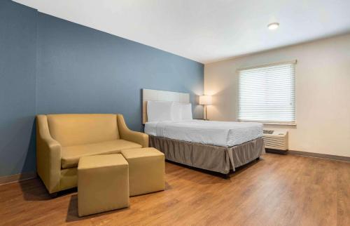 Extended Stay America Suites - New Orleans - Airport - I-10 في كينير: غرفة نوم بسرير وكرسي في غرفة