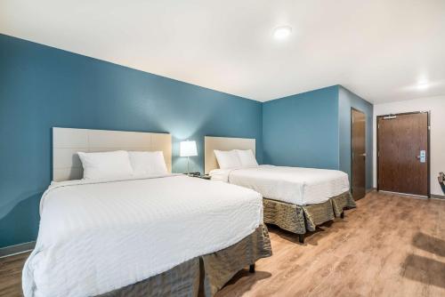 2 łóżka w pokoju z niebieskimi ścianami w obiekcie Extended Stay America Select Suites - Orlando - Kissimmee w Orlando