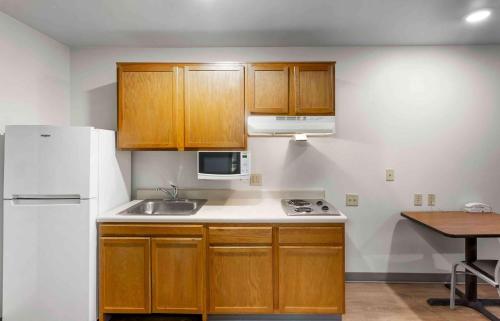 a kitchen with wooden cabinets and a white refrigerator at Extended Stay America Select Suites - Ogden in Ogden