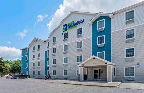 a large white and blue hotel with a parking lot at Extended Stay America Select Suites - Pensacola - Northeast in Pensacola