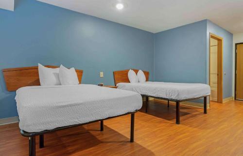 two beds in a room with blue walls at Extended Stay America Select Suites - Fayetteville - West in Fayetteville