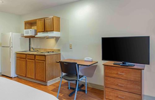 a kitchen with a desk with a tv and a table with a chair at Extended Stay America Select Suites - Fayetteville - West in Fayetteville