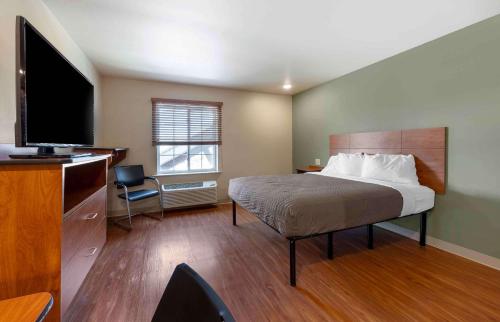 Extended Stay America Select Suites - Oklahoma City - West في مدينة اوكلاهوما: غرفة فندقية بسرير وتلفزيون بشاشة مسطحة