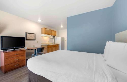 a hotel room with a bed and a flat screen tv at Extended Stay America Select Suites - Orlando - East in Orlando