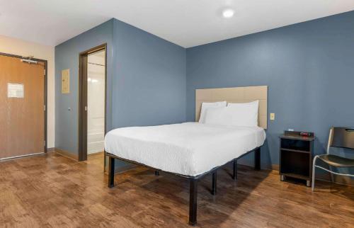 a blue bedroom with a bed and a chair at Extended Stay America Select Suites - Orlando - South in Orlando