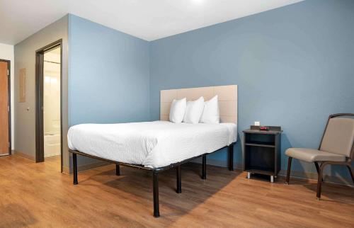 łóżko w niebieskim pokoju z krzesłem w obiekcie Extended Stay America Select Suites - Panama City - Callaway w mieście Callaway