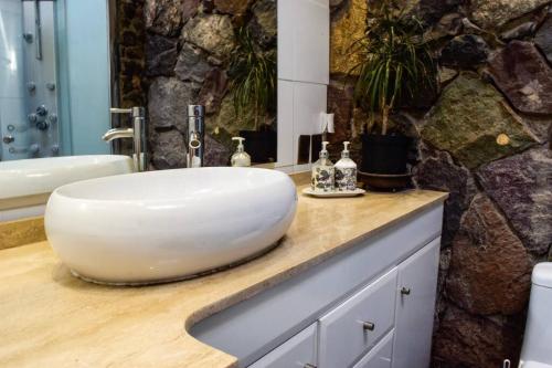 baño con lavabo blanco en la encimera en Iluminada casa de piedra entre bosque y río, en Lo Barnechea