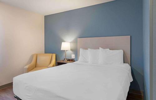 Extended Stay America Suites - Redlands في ريدلاندز: غرفة نوم بسرير ابيض كبير وكرسي