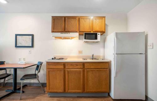 a kitchen with a white refrigerator and a table at Extended Stay America Select Suites - Tallahassee - Northwest in Tallahassee