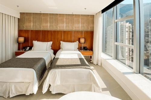 two beds in a hotel room with large windows at Hotel Nacional in Rio de Janeiro