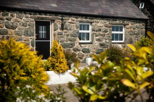 Cabaña de piedra con puerta negra y ventanas en RB Contractor Stays - Onnen, en Pwllheli