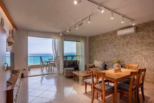 a living room with a table and chairs and the ocean at Salty Loft in Hanioti