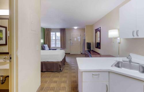 a hotel room with a bed and a kitchen with a sink at Extended Stay America Suites - Fayetteville - Owen Dr in Fayetteville