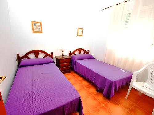 2 bedden in een kamer met paarse lakens bij Apartamentos Noria Familias y Parejas Gold in Conil de la Frontera
