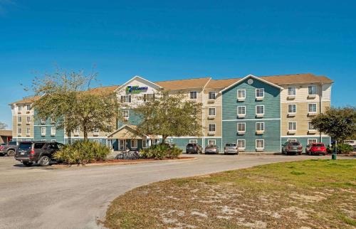 a large building with cars parked in a parking lot at Extended Stay America Select Suites - Fort Walton Beach in Fort Walton Beach