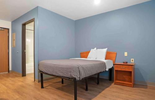 1 dormitorio con cama y pared azul en Extended Stay America Select Suites - Fort Walton Beach en Fort Walton Beach