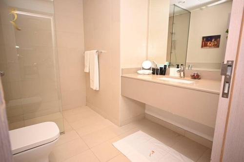 a bathroom with a sink and a toilet and a mirror at Rossa Yas 1BR Haven - Chic Luxe Escape in Abu Dhabi