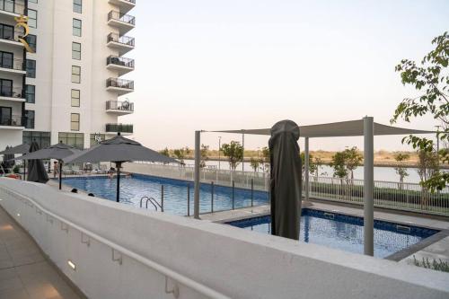 a swimming pool with umbrellas next to a building at Rossa Yas 1BR Haven - Chic Luxe Escape in Abu Dhabi
