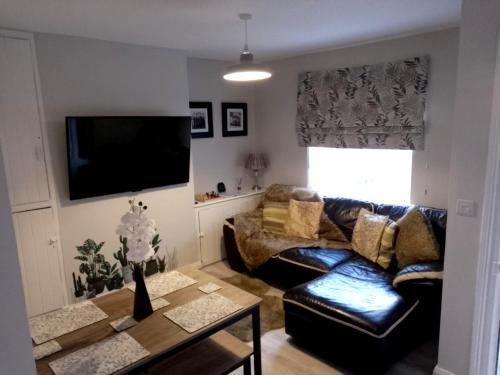 sala de estar con sofá de cuero y mesa en Máire Toiréasa – cosy refurbished property in the Gaeltacht Quarter, en Belfast