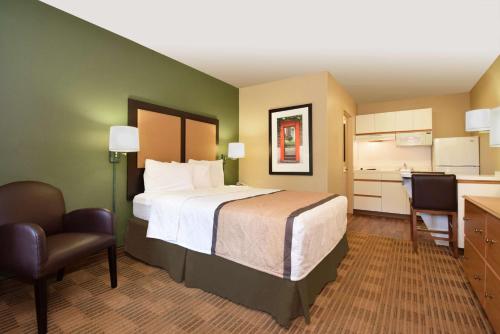 a hotel room with a large bed and a kitchen at Extended Stay America Suites - Raleigh - North Raleigh - Wake Forest Road in Raleigh