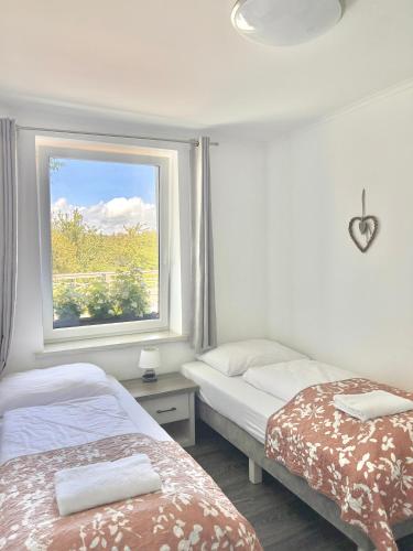 two beds in a room with a window at Apartamenty Golf Dyndeby in Neksø