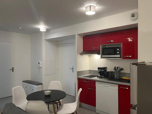 uma cozinha com armários vermelhos, uma mesa e cadeiras em Calm in Tours - Appartement T2 em Tours