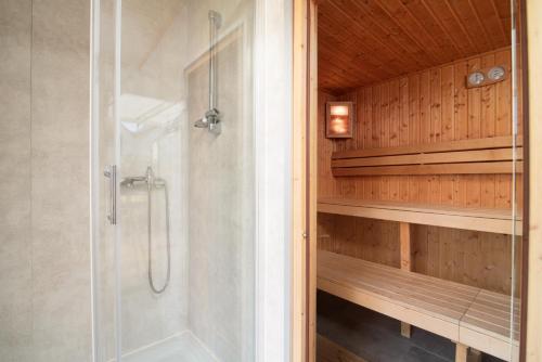a walk in shower in a bathroom with wooden walls at Fantazja&spa in Dębki
