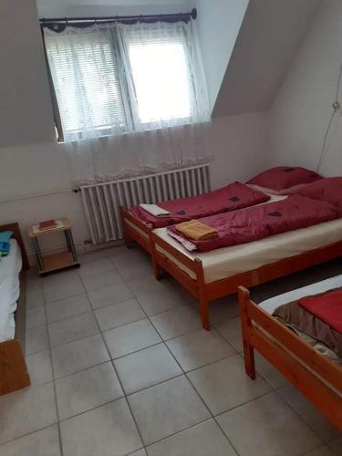 a bedroom with two beds and a window at Pihenés a Malomtónál privát bérlemény in Tapolca