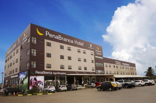 ein großes Gebäude mit Autos auf einem Parkplatz in der Unterkunft Pena Branca Hotel e Eventos in Santo Antônio de Jesus