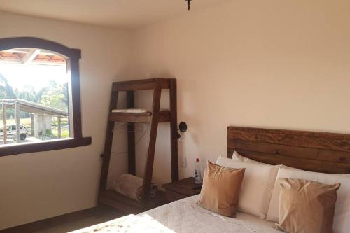 Schlafzimmer mit einem Bett mit einem Fenster und einer Leiter in der Unterkunft Chalé Serra do Ouro in Diamantina
