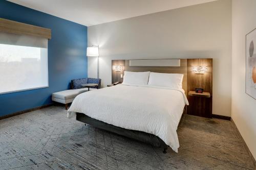 a bedroom with a white bed and a blue wall at Holiday Inn Express Holly Springs - Raleigh Area by IHG in Holly Springs