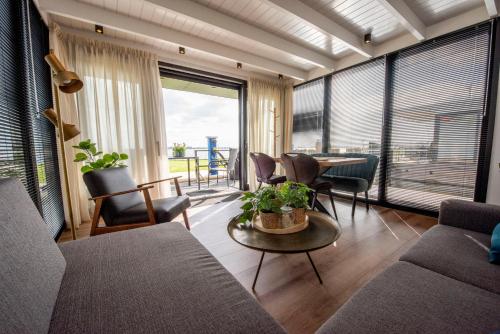 a living room with a couch and a table and chairs at Vakantiewoonboot De Waterparel in Offingawier