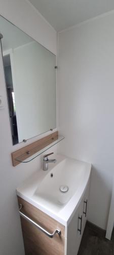y baño con lavabo blanco y espejo. en mobil home 708 chez Eric et Valérie, calme et ombragé. en Les Mathes