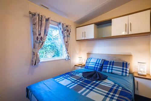 a bedroom with a blue bed and a window at Mobil-home Excellence - 3 Chambres in Chaumont-sur-Loire