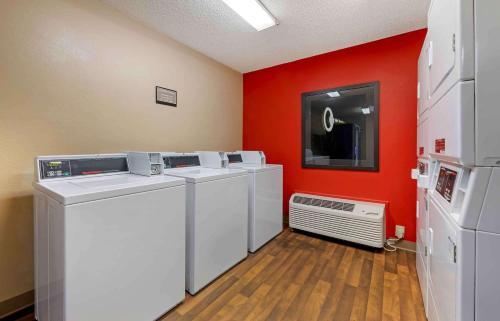 a laundry room with white washers and a red wall at Extended Stay America Suites - Daytona Beach - International Speedway in Daytona Beach