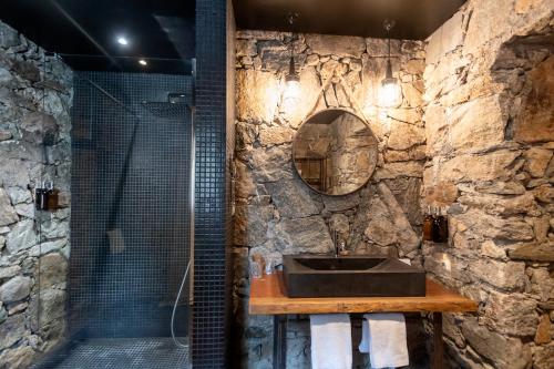 a stone bathroom with a sink and a shower at Hôtel Case Latine in Lama