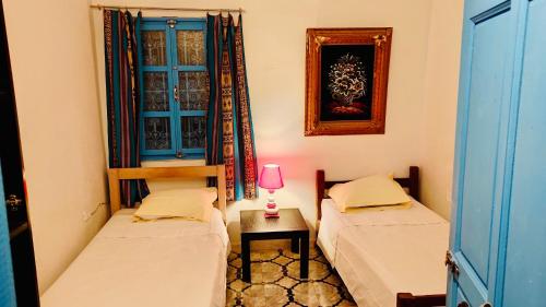 um quarto com duas camas e um candeeiro sobre uma mesa em Appartement Berbère em Tozeur