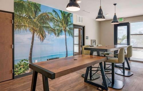 une salle à manger avec une table et une fresque murale de palmiers dans l'établissement Extended Stay America Premier Suites - Melbourne - Palm Bay, à West Melbourne