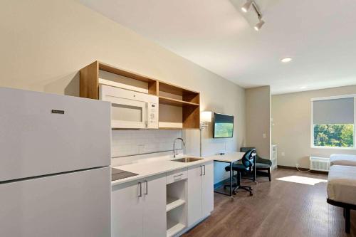 a kitchen with a white refrigerator and a dining room at Extended Stay America Premier Suites - Melbourne - Palm Bay in West Melbourne