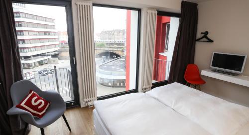 a hotel room with a bed and a large window at Smartcity Designhotel in Hannover