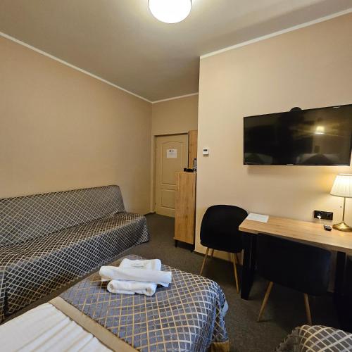 a hotel room with a bed and a desk and a tv at Willa Kłodzko-Zacisze - sauna, siłownia, komnata solna, parking in Kłodzko