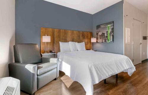Extended Stay America Premier Suites - Orlando - Sanford في سانفورد: غرفة نوم بسرير ابيض كبير وكرسي