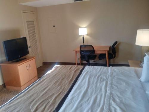 a hotel room with a bed and a desk and a television at Extended Stay America Suites - Jacksonville - Deerwood Park in Jacksonville
