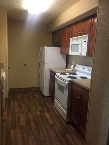 a kitchen with white appliances and wooden cabinets at Extended Stay America Suites - Jacksonville - Deerwood Park in Jacksonville