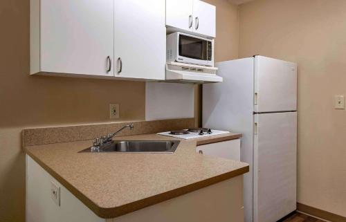 a kitchen with a sink and a microwave and a refrigerator at Extended Stay America Suites - Jacksonville - Riverwalk - Convention Center in Jacksonville