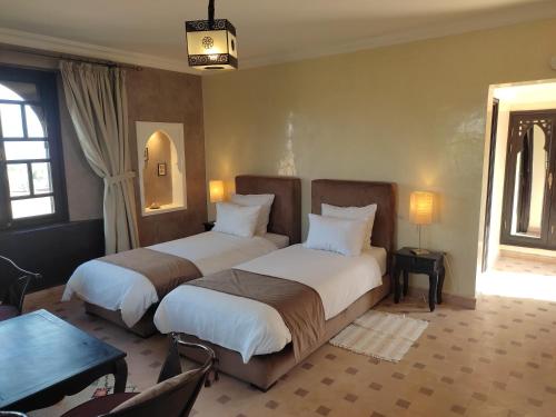 two beds in a room with two windows at Kasbah ATFEL in Ourika