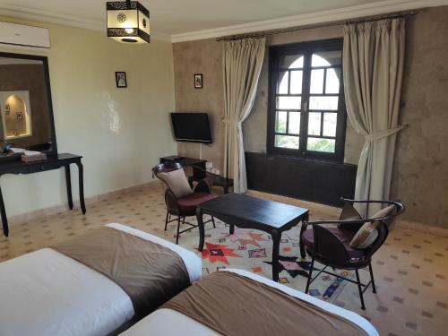 a room with two beds and a table and chairs at Kasbah ATFEL in Ourika