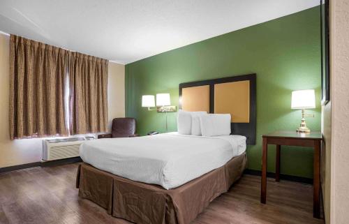 a hotel room with a large bed and a green wall at Extended Stay America Suites - Pensacola - University Mall in Pensacola