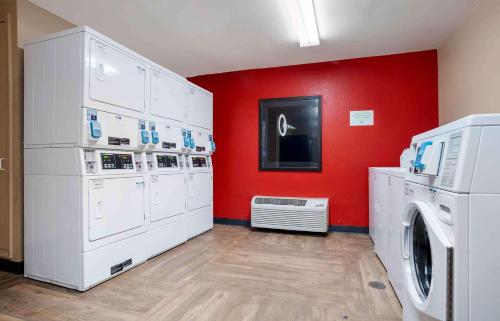 a laundry room with white washers and a red wall at Extended Stay America Suites - Pensacola - University Mall in Pensacola