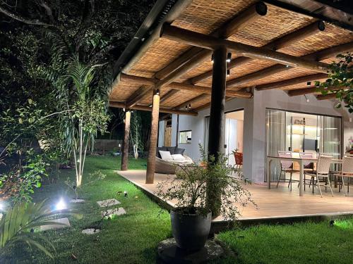 a house with a wooden patio with a table and chairs at CASA ALTO DA ENSEADA PRAIA DO FORTE in Praia do Forte